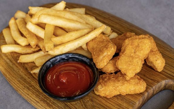 Kids chicken nuggets with fries and tomato sauce on a board